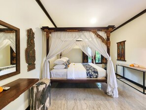 Una cama con dosel, una mesita de noche de madera y un espejo en la pared.
