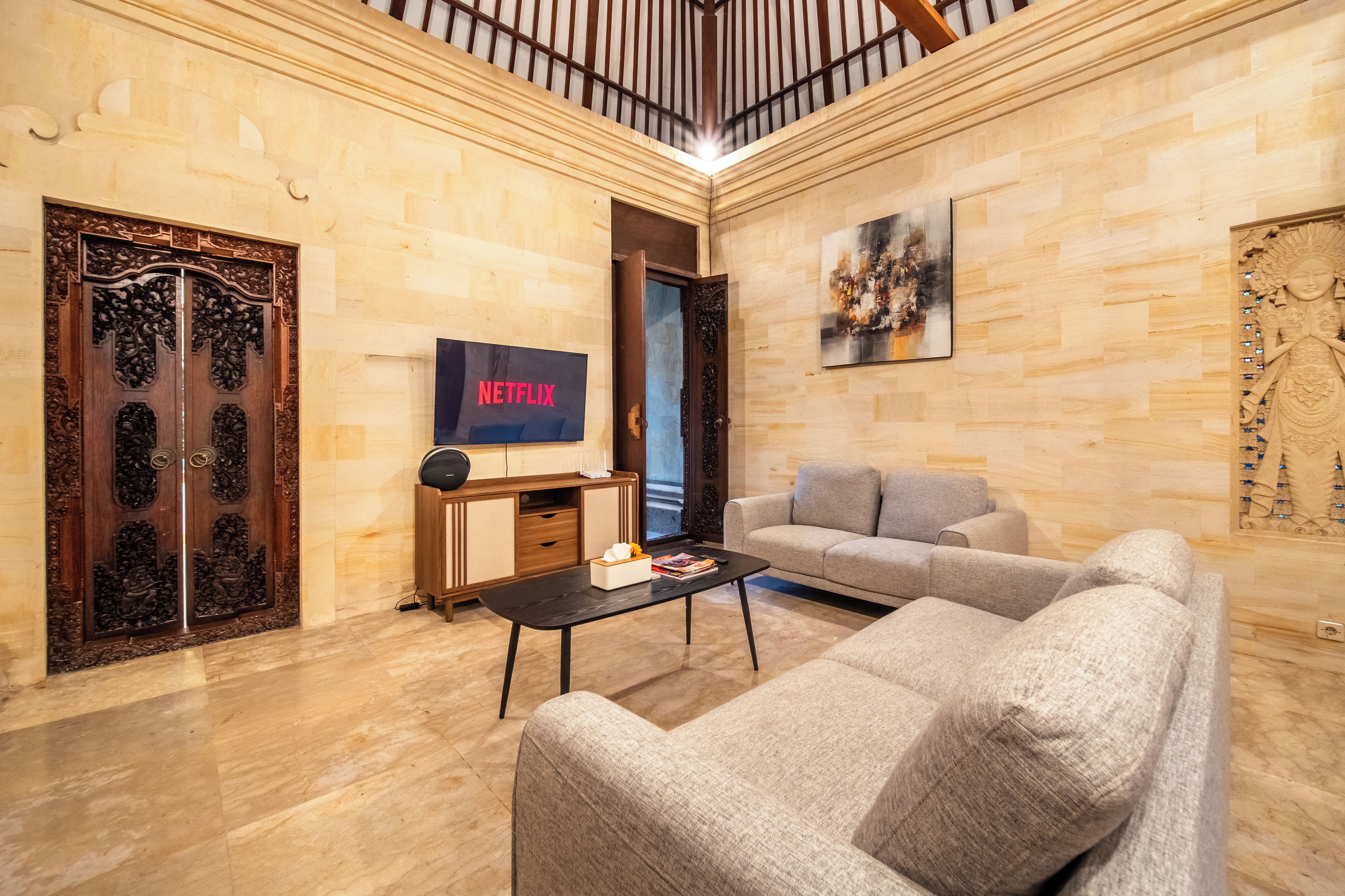 Un salon comprenant un canapé, une table basse, un téléviseur et une porte en bois ornée de sculptures complexes.