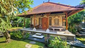 A traditional building with a tiled roof, a porch with chairs, and a stone pathway leading to the entrance. - Villa Hibiscus Sanur by Nagisa Bali (Denpasar)