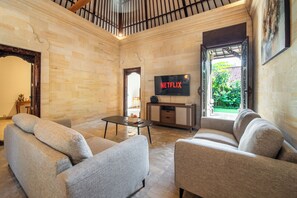 Un salon doté d’un téléviseur à écran plat, de canapés gris, d’une table basse et d’un meuble TV en bois.