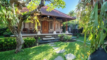 Uma casa tradicional com telhado de telhas, varanda de madeira e um jardim com degraus de pedra.