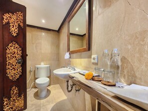 Un baño con inodoro, lavamanos, espejo y puerta decorativa.