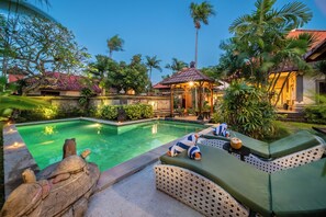 A swimming pool with lounge chairs and a tiki hut. - Villa Hibiscus Sanur by Nagisa Bali (Denpasar)
