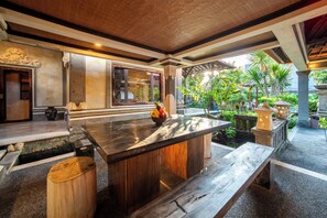 A modern kitchen with a central island, wooden stools, and a view of a lush garden. - Villa Hibiscus Sanur by Nagisa Bali (Denpasar)