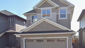 A two-story house with a garage, a visible address number, and a clear driveway.