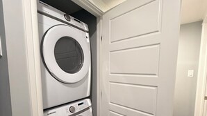 A laundry room with two stacked washers and dryers, a white door, and a carpeted floor.