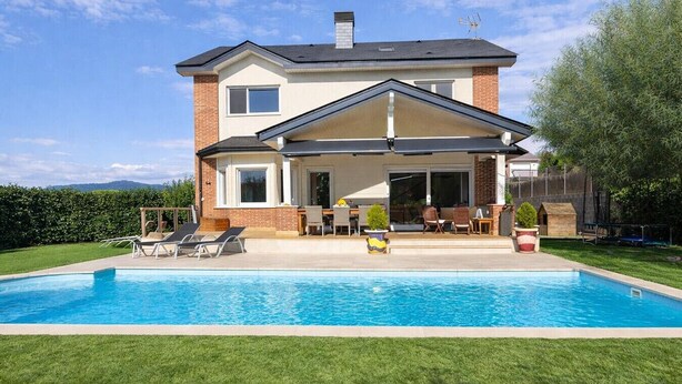 Une maison à deux étages avec une piscine, un patio couvert et une pelouse bien entretenue.