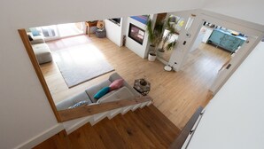 Un appartement moderne doté d’un escalier, d’un espace de vie avec un canapé, d’un coin repas et d’une cuisine.