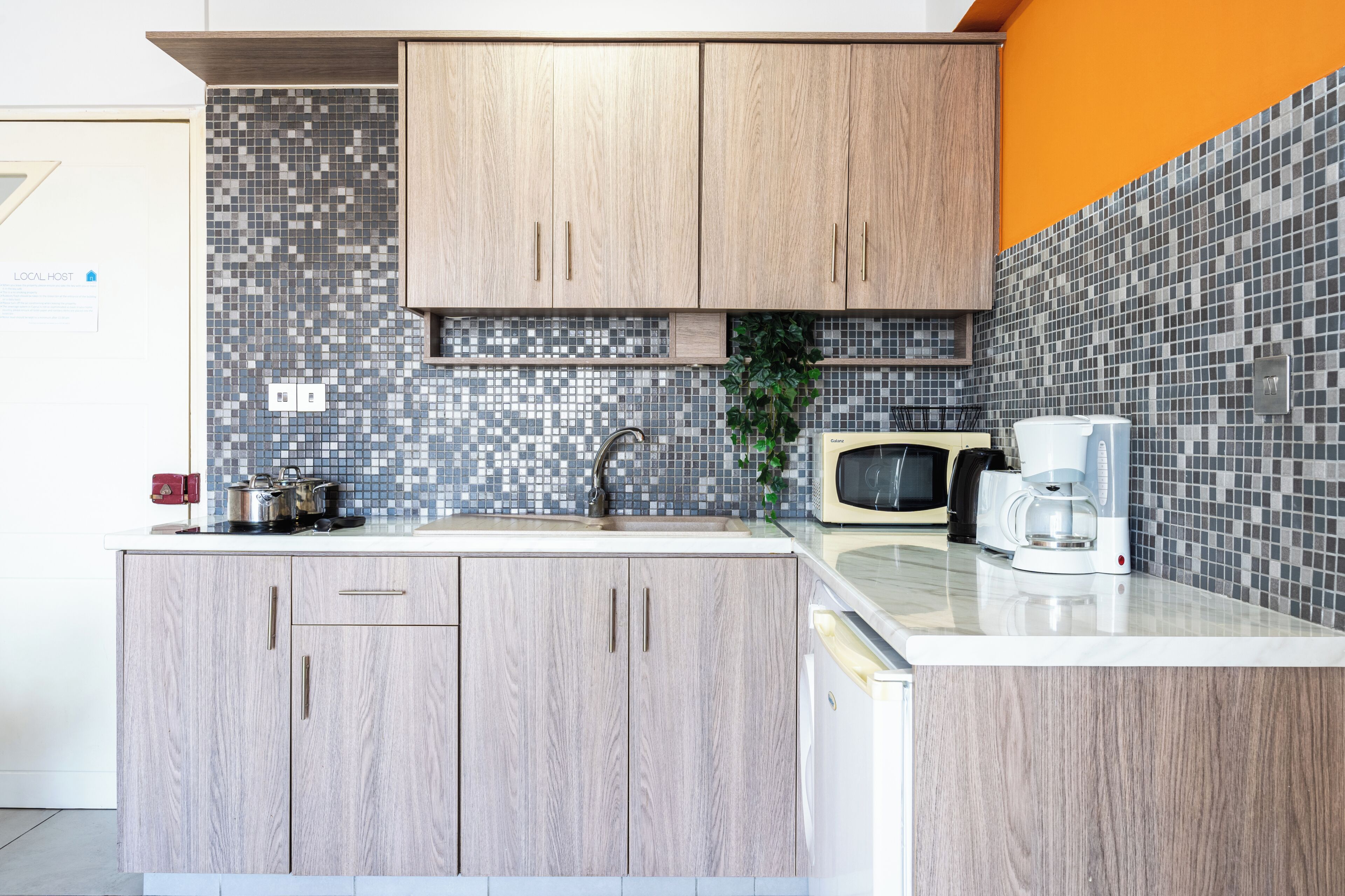 Une cuisine moderne avec des meubles en bois, un pare-feu en carrelage et un four à micro-ondes.