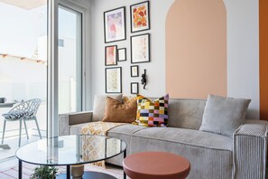 A living room with a sofa, a glass coffee table, and a chair. - Made with love 1-BR By Finikoudes Beach (Larnaca)