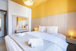 A hotel room with a large bed, a bedside table with a lamp, a mirror, and a wall-mounted shelf with toiletries. - Made with love 1-BR By Finikoudes Beach (Larnaca)