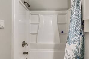 A bathroom with a bathtub, a shower, a toilet, and a shelf with a blue item. - Bayside Waterfront Retreat in Ocean City! (Ocean City)