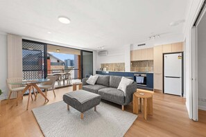 Eine moderne Wohnung mit Wohnbereich, Küchenzeile und einem Balkon mit Blick.