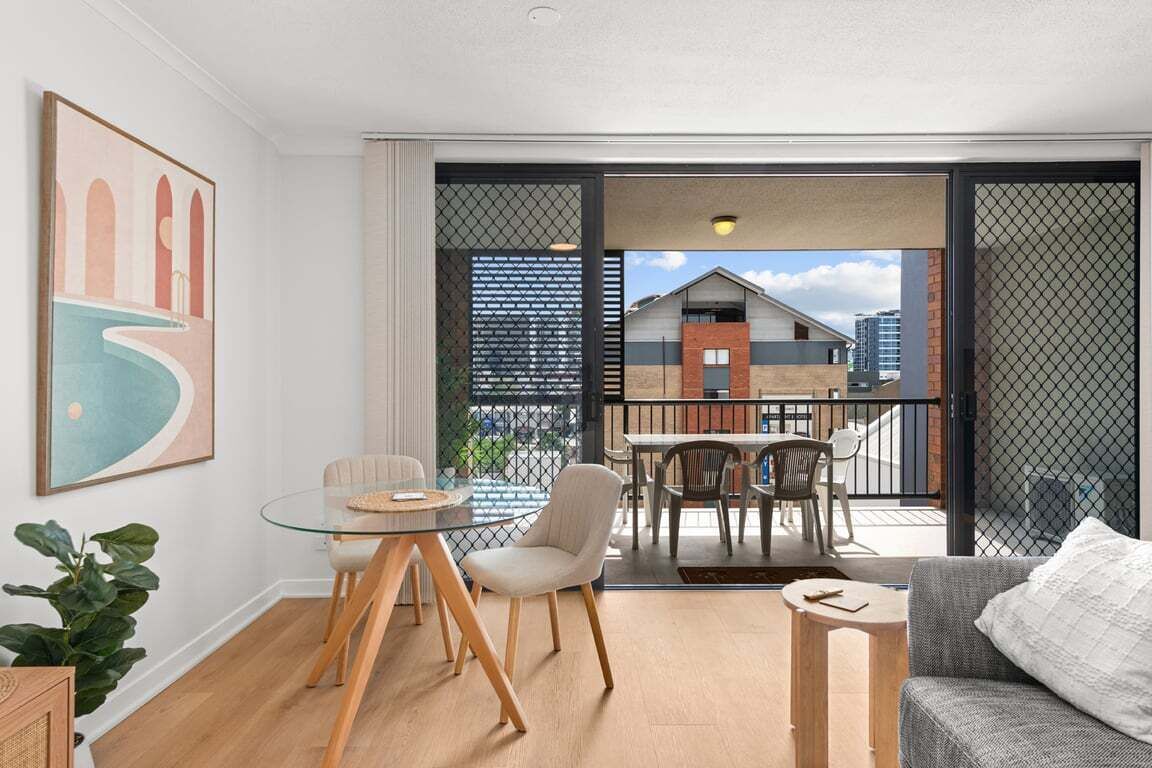 Un salon moderne avec une table à manger en verre, un canapé et un balcon offrant une vue sur les immebles.