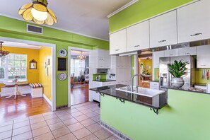 Une cuisine avec des murs verts, des armoires blanches, un plan de travail noir et un évier.