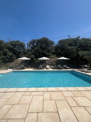 A rectangular swimming pool with clear blue water, surrounded by stone tiles. There are three white umbrellas and two lounge chairs. - Gite for 4 people in the countryside each room has its own bathroom and private wc (Visan)