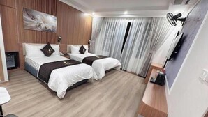 A hotel room with two beds, a desk, a chair, a TV, and a window with curtains. - One Villa Hotel 6 (Hanoi)