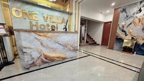 A marble reception desk with 'ONE VILLA Hotel' signage, a staircase, and a large abstract mural. - One Villa Hotel 6 (Hanoi)