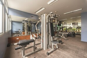 Et fitnesscenter med forskellige træningsmaskiner, spejle og løbebånd.