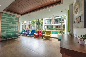 A modern lobby with colorful chairs, a reception desk, and a view of a pool and buildings. - Patong City No Deposit Or Extra Charges C211 (Pa Tong)