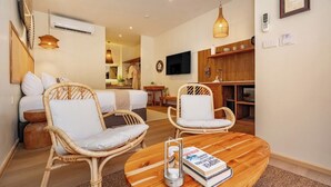 Una sala de estar moderna con muebles de mimbre, una mesa redonda de madera y un televisor de pantalla plana montado en la pared.