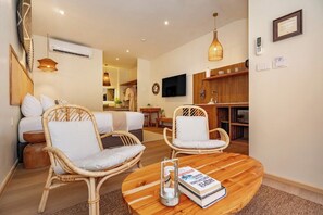 A modern living room with wicker furniture, a round wooden coffee table, and a flat-screen TV mounted on the wall. - Patong City No Deposit Or Extra Charges C211 (Pa Tong)