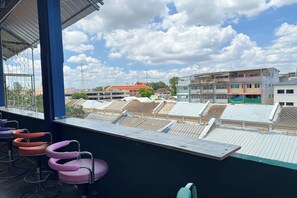 A balcony with metal railings and a view of buildings with red roofs. - Roxx Social Hostel, Cafe & Bistro (Bangkok)