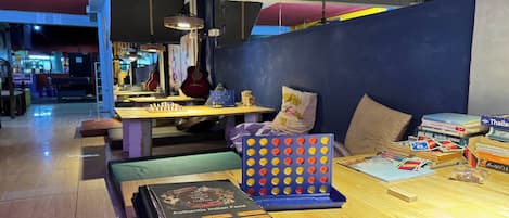 A cozy restaurant with a wooden table, cushions, and a board game.