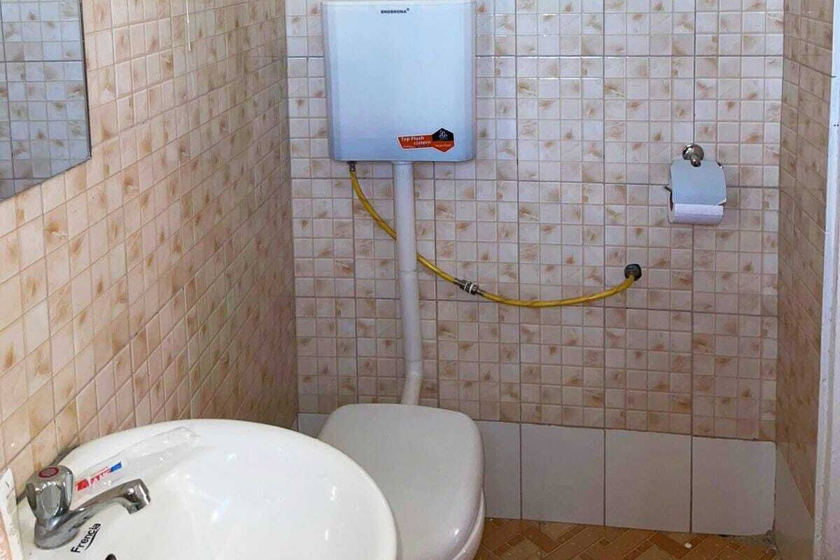 A bathroom with a toilet, a sink, a mirror, and a water heater.