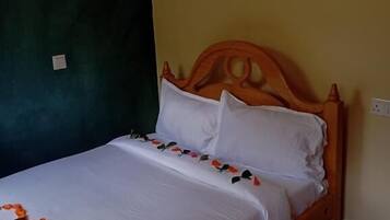 A single bed with a wooden headboard, white bedding, and a small towel on the footboard.