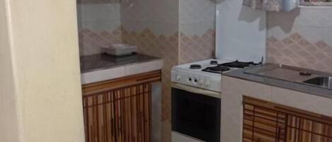 Una cocina compacta con estufa, horno y armarios de madera.