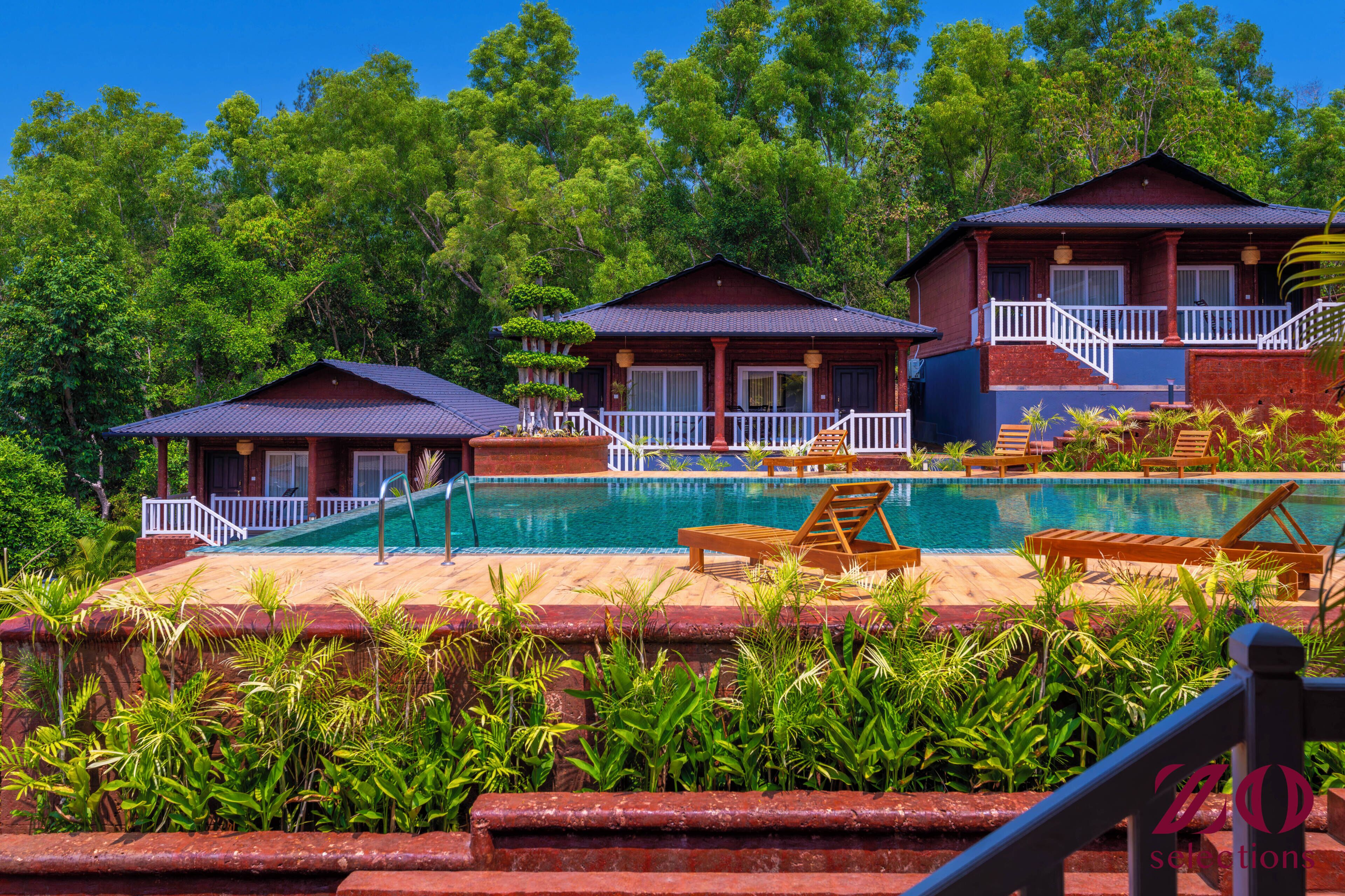 Et resort med swimmingpool, træterrasse og to gæstehuse med altaner.