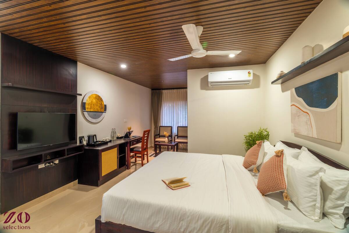 Une chambre d’hôtel équipée d’un lit, d’une télévision, d’un bureau et d’un ventilateur de plafond.