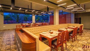 A restaurant with a long communal dining table, individual tables, and booths. - Zo Selections Gokarna by Zostel (Gokarna)