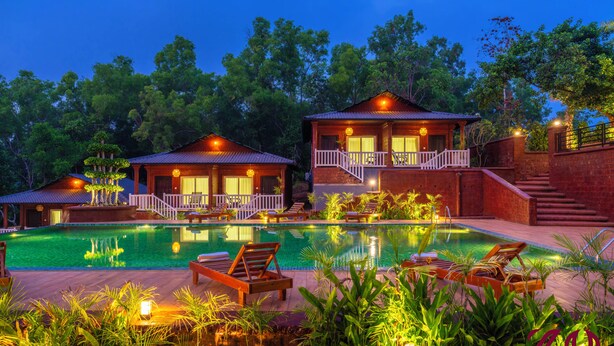 A pool area with lounge chairs, a wooden deck, and two buildings with balconies. - Zo Selections Gokarna by Zostel (Gokarna)