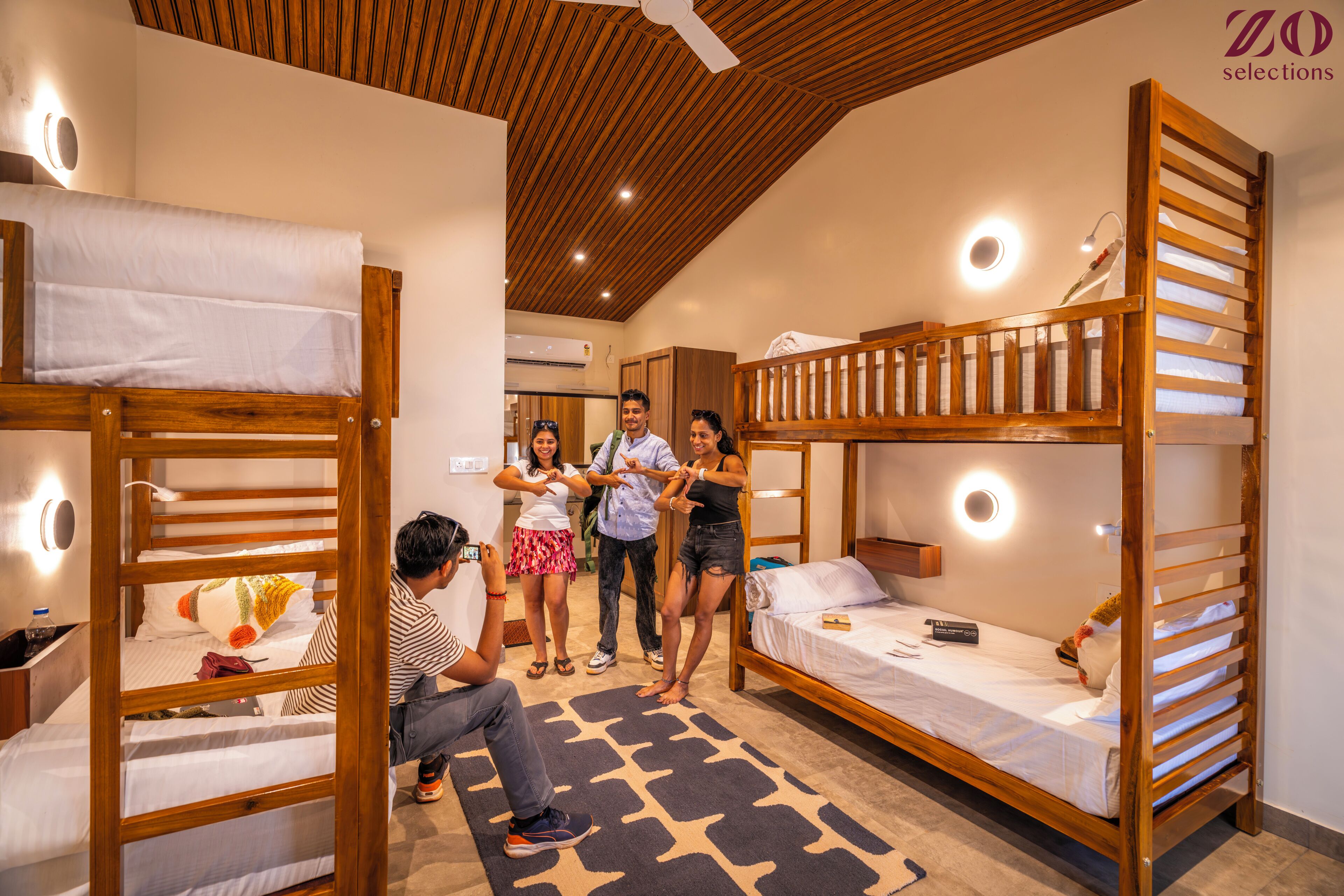 A room with bunk beds, a small desk, and a wall-mounted light fixture.