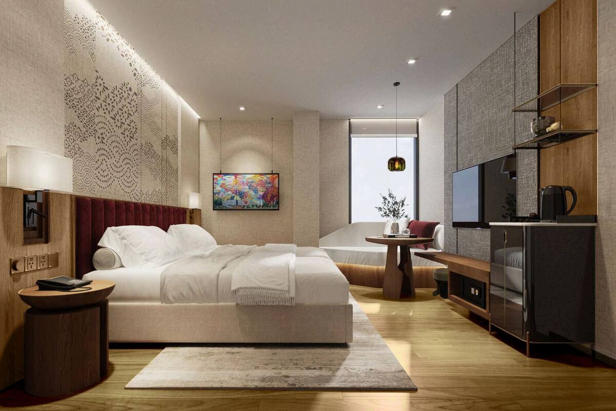 A modern hotel room with a large bed, a TV, a small table, and a window.