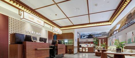Eine Hotelhalle mit einer Rezeption, einer Sitzecke und einer Wand mit Kunstwerken.