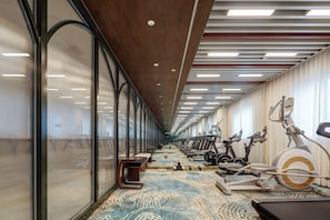 Une salle de sport équipée de matériel d’exercice, de bancs et recouverte d’un tapis à motifs.
