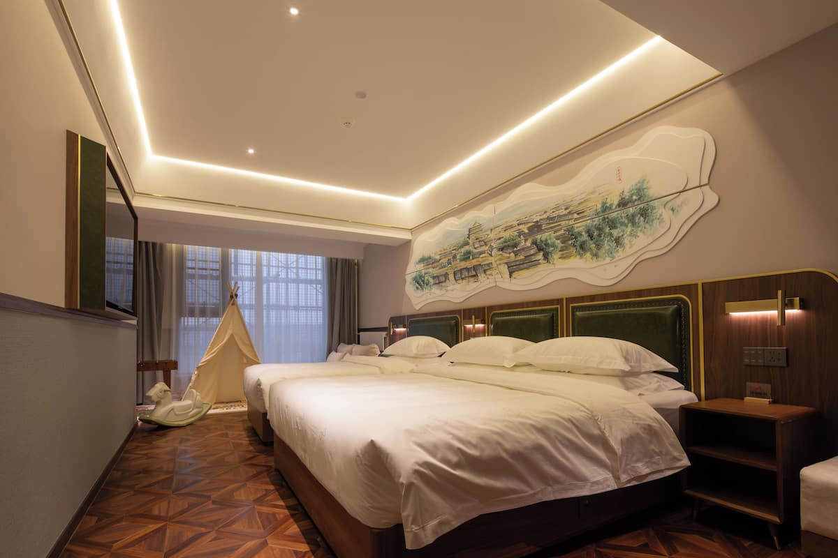 Ein Hotelzimmer mit einem großen Bett, einem Wandbild, Holzboden und einem mit Vorhängen versehenen Fenster.
