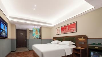 Habitación de hotel con cama, mesita de noche, minibar, televisor y un cuadro en la pared.