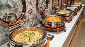 Uma mesa de buffet com diversos pratos em recipientes de metal.
