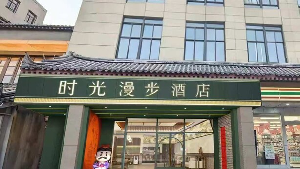 L’entrée d’un hôtel, conçue dans un style architectural chinois traditionnel, avec un auvent vert et une enseigne en caractères chinois.