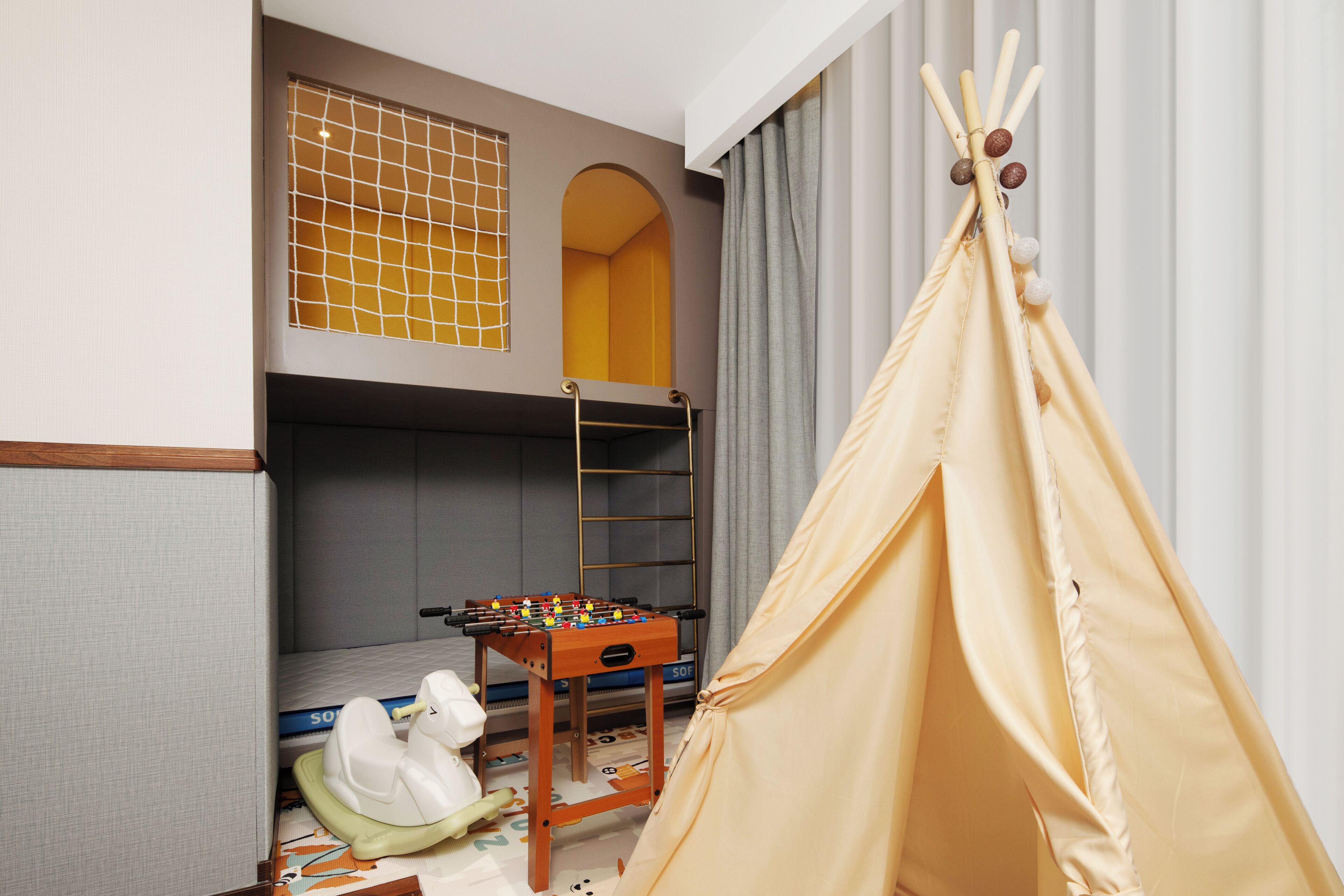 Ein Kinderzimmer mit Etagenbetten, einem Kicker und einem Zelt.