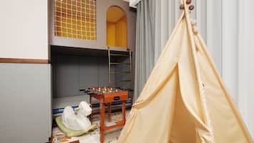 Ein Kinderzimmer mit Etagenbetten, einem Kicker und einem Zelt.