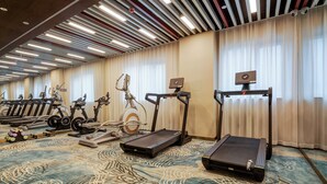 A hotel fitness center with various exercise equipment, including treadmills, stationary bikes, and weight machines.