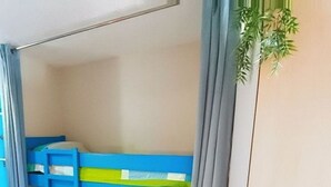 Un llit superposat amb una escala, una tauleta de nit i una planta.