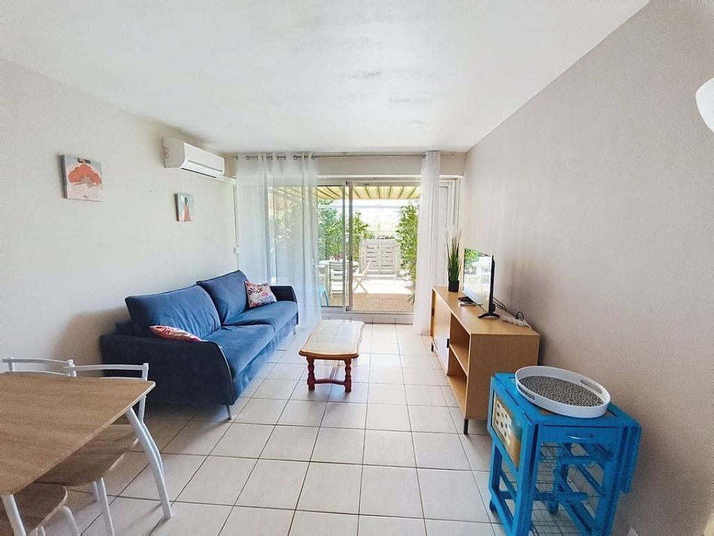 A living room with a sofa, a coffee table, a TV stand, and a blue chair.