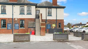 A two-story building with a brick facade, multiple windows, and a signboard advertising food and drink. - The Slow & Easy (Northwich)