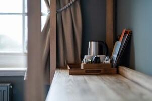 A wooden tray with a kettle, a cup, and a magazine holder on a window sill.